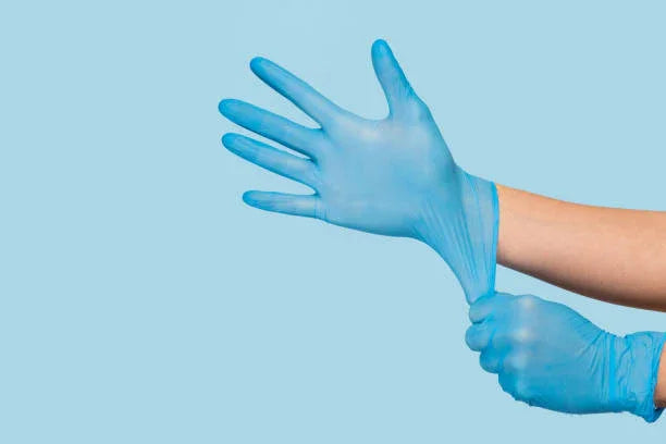 A hand wearing a blue latex glove against a blue background.